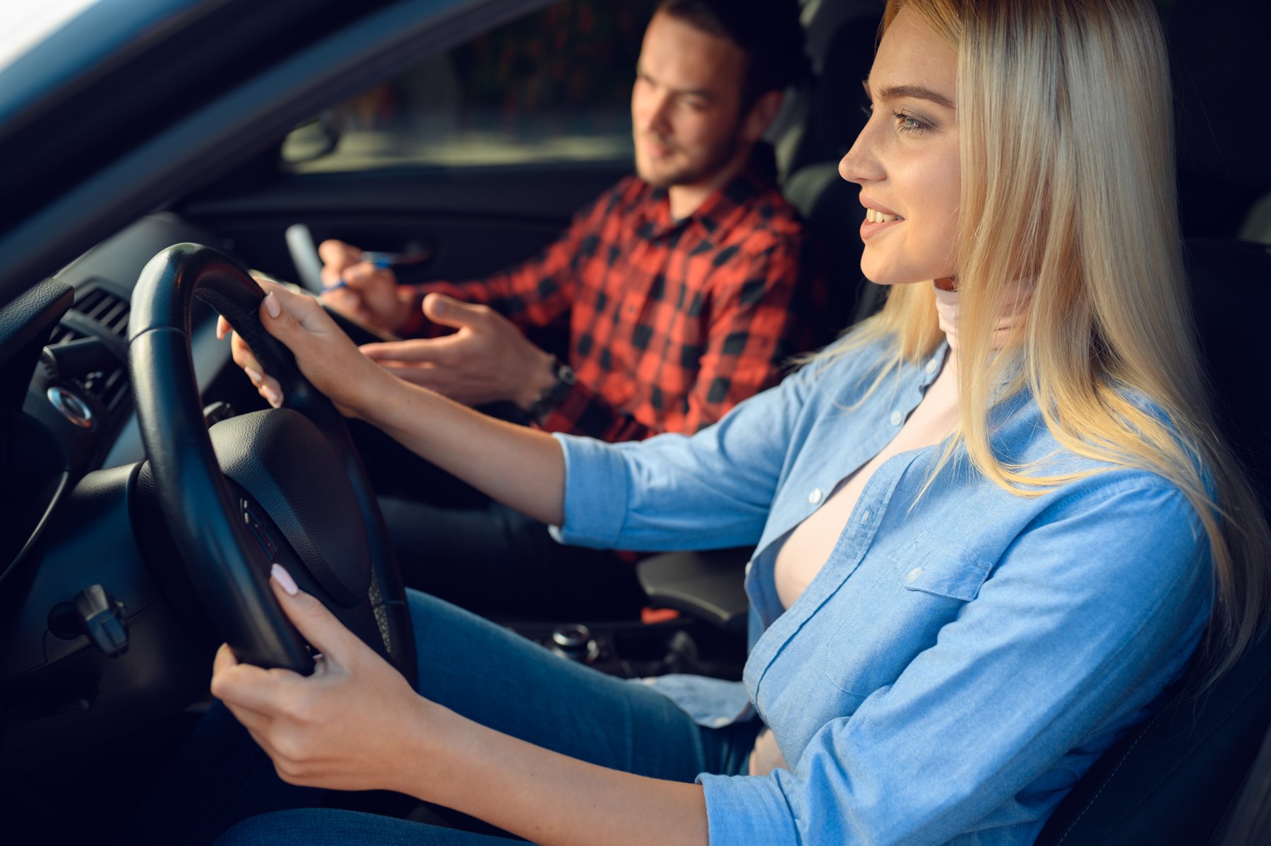 Fahrschülerin am Steuer mit Fahrlehrer