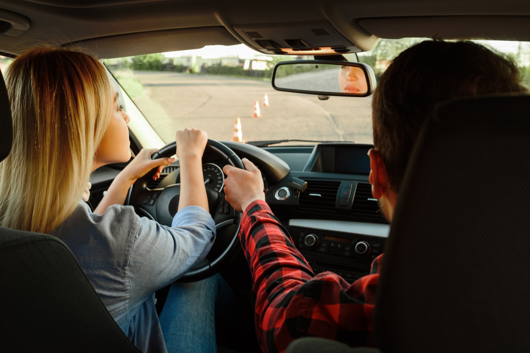 Fahrlehrer unterstützt eine Fahrschülerin beim Fahren